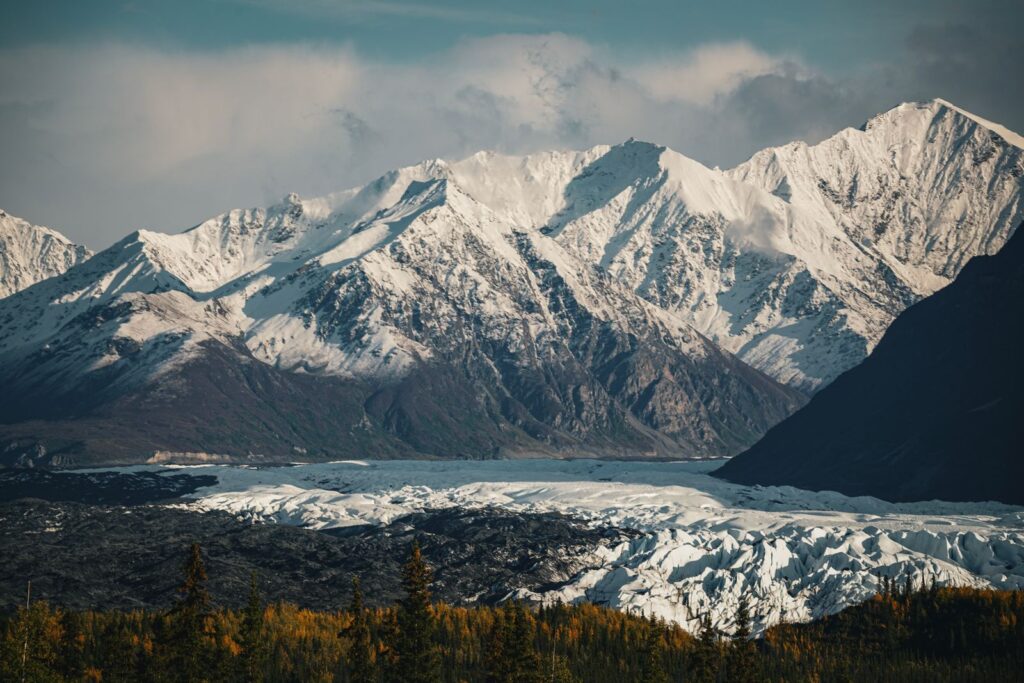 Breathtaking view of snow-capped mountains with a glacier below, captured in serene