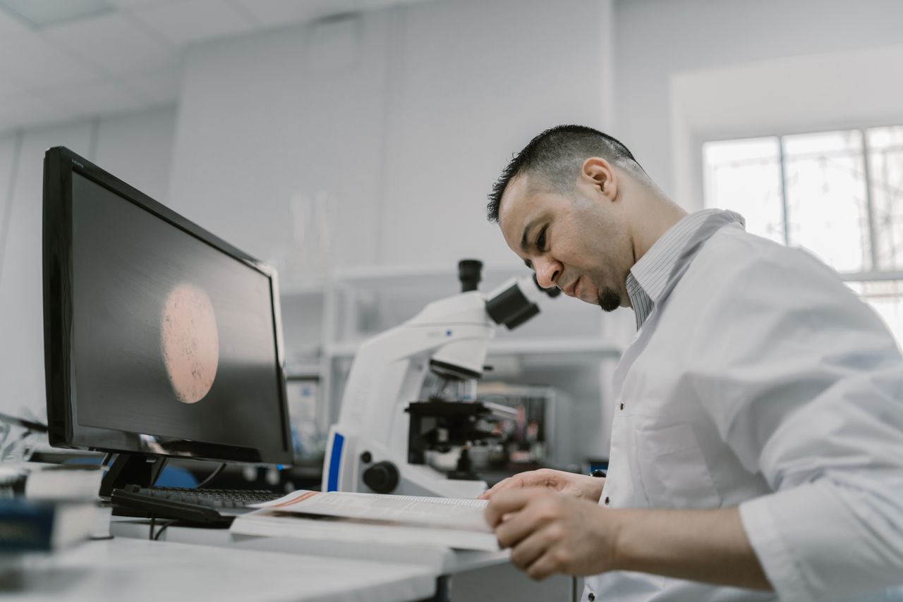 Researcher reading in a laboratory beside a microscope