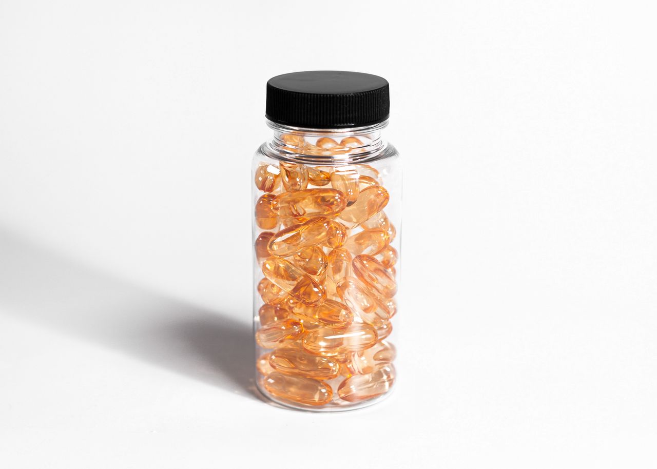 Transparent bottle filled with amber capsules