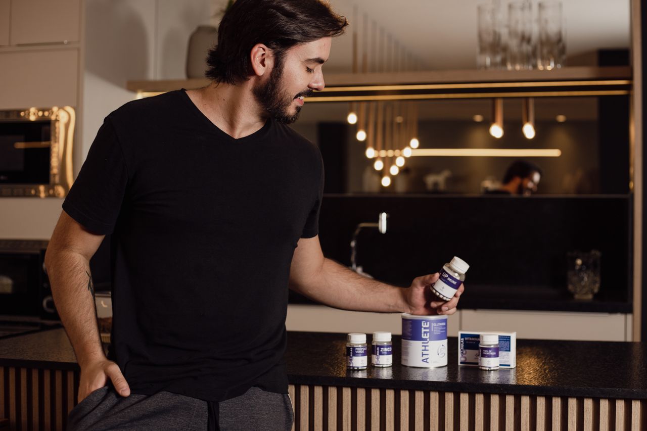 Man examining supplement bottles on a kitchen counter