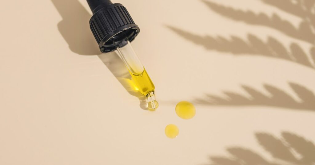 Dropper releasing drops of golden CBD oil