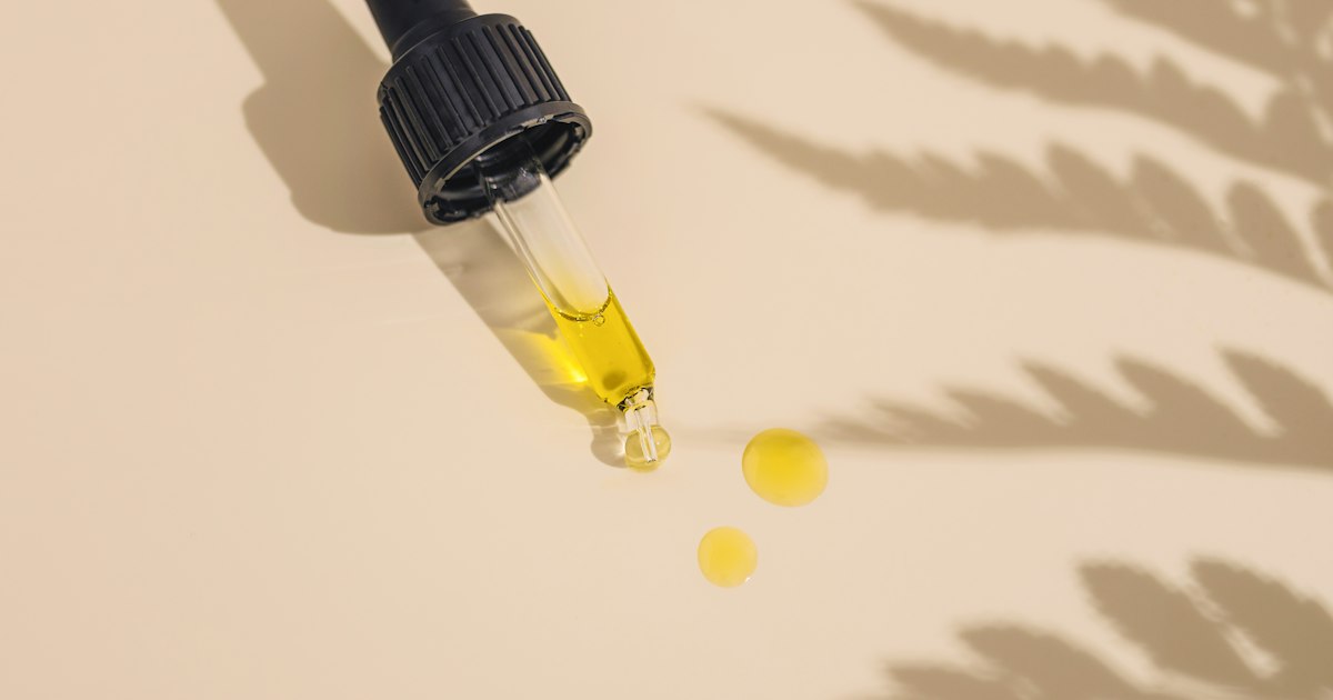 Dropper releasing drops of golden CBD oil