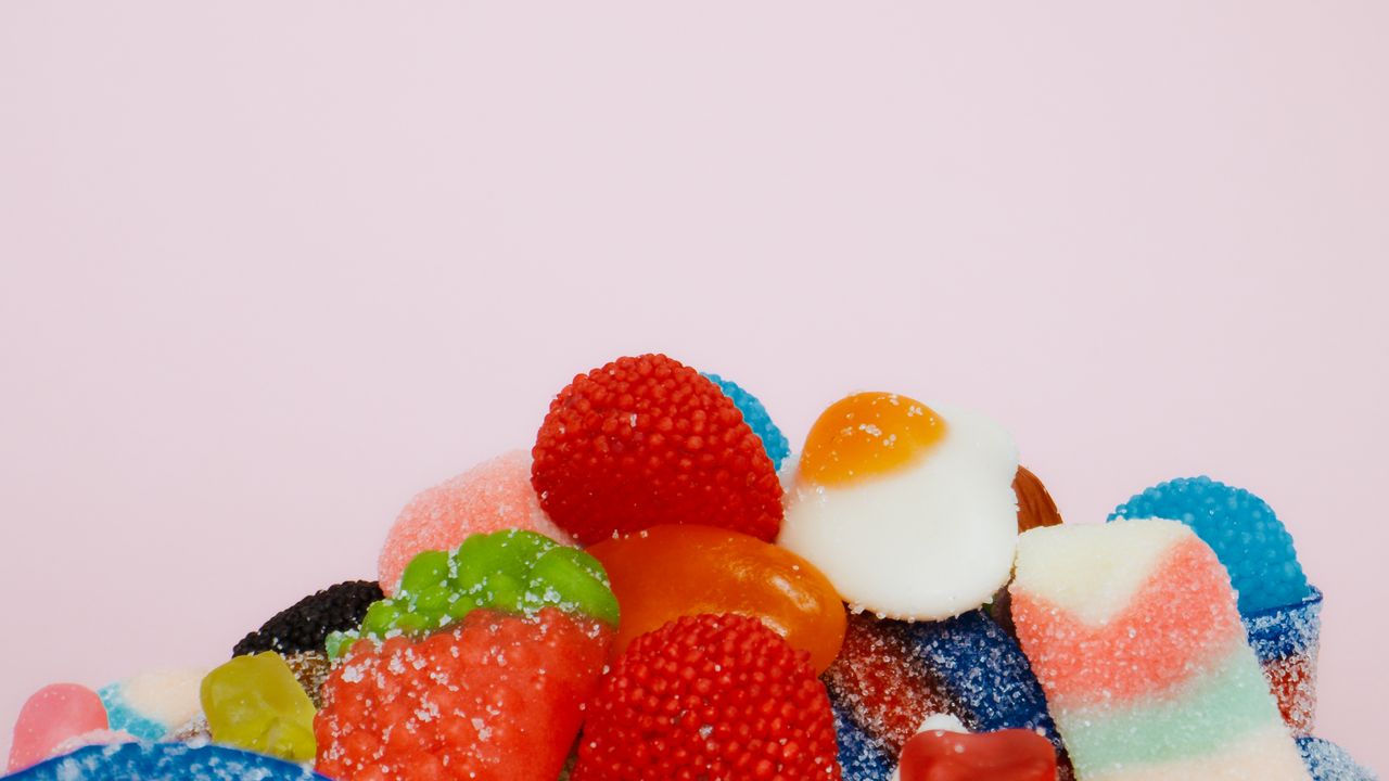 Assorted sugar-coated gummy candies on a pastel background