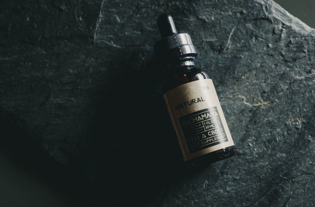 CBD tincture bottle on a dark stone background