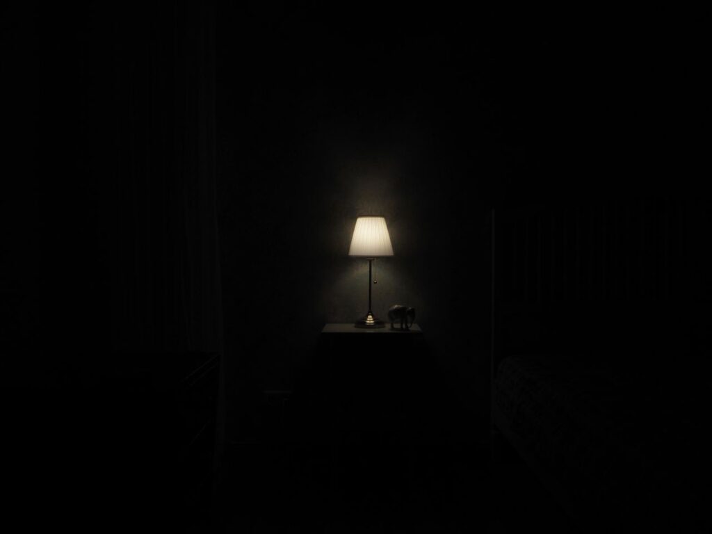 Lamp glowing on a nightstand in a dark room