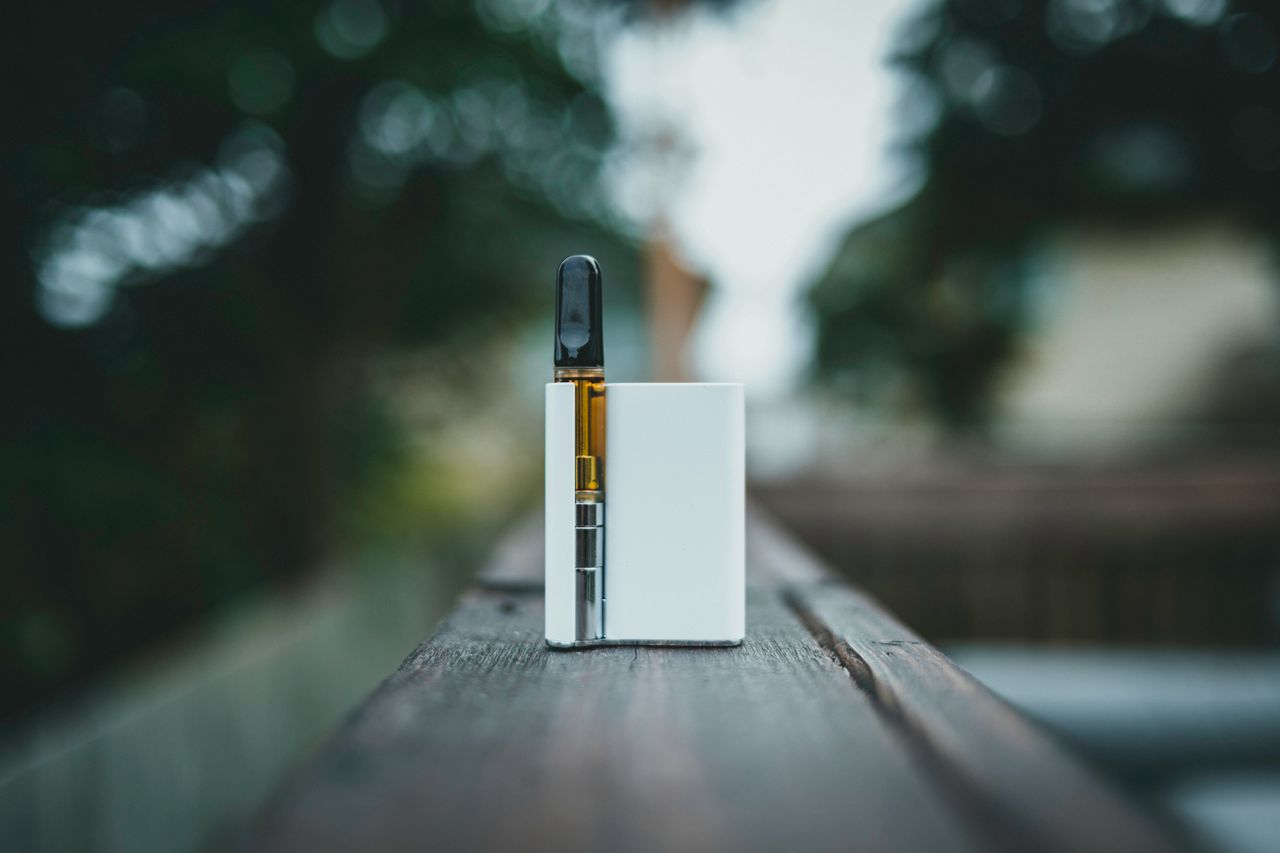 Vape device resting on a wooden surface outdoors