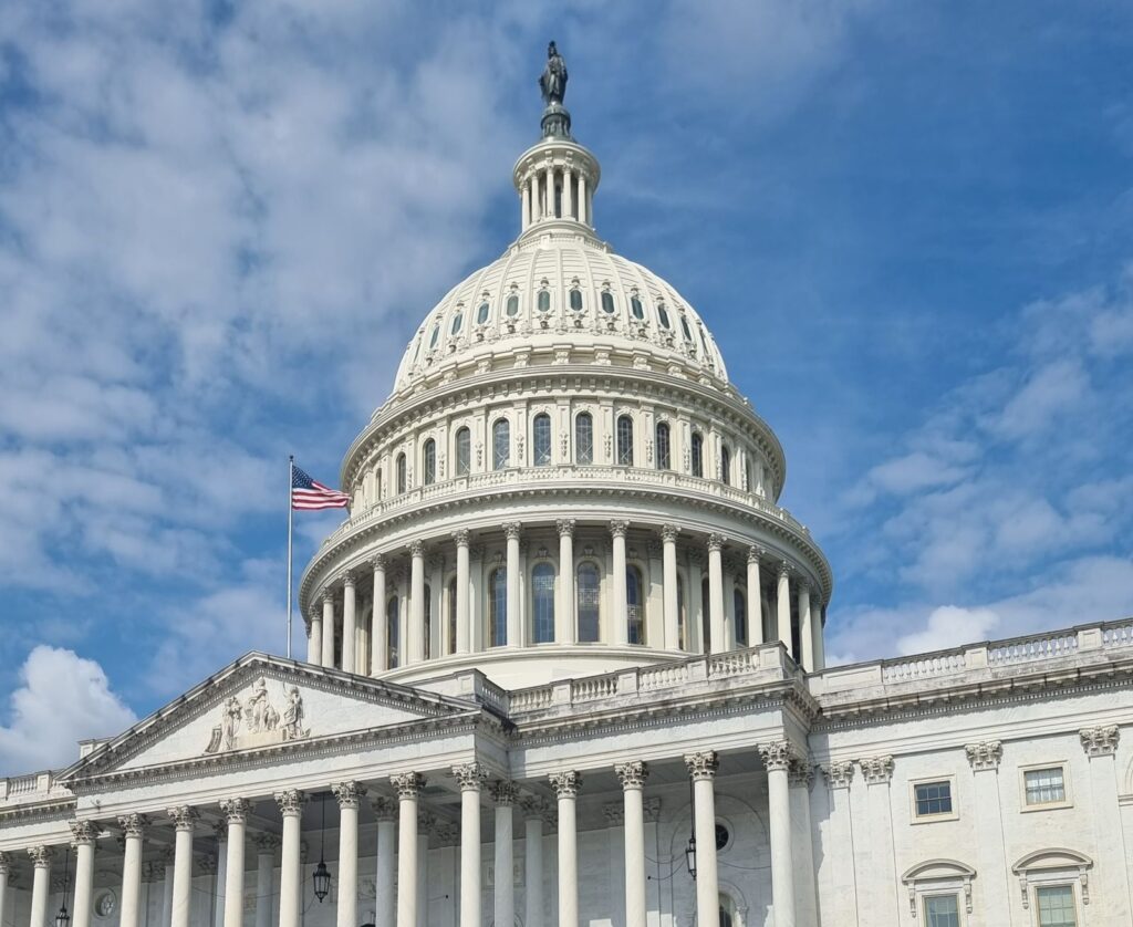A striking view of the US Capitol dome with flag and blue sky in Washington, DC