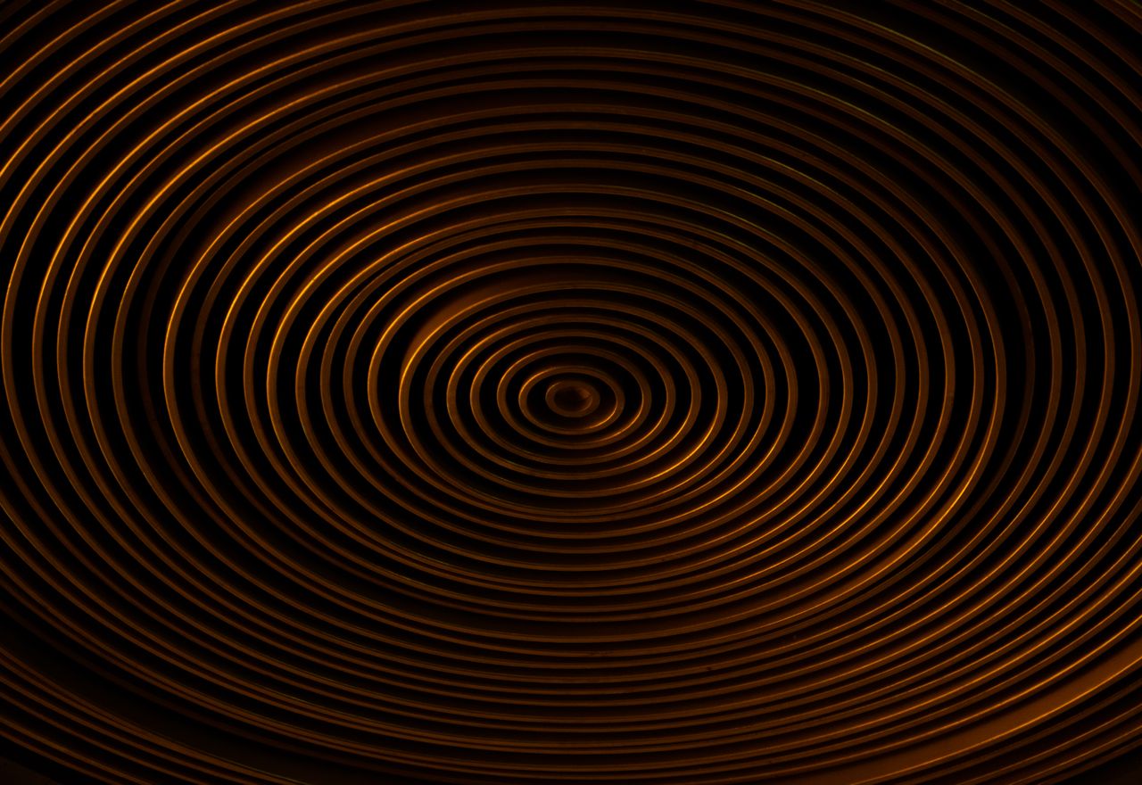 Concentric copper spirals on a dark background