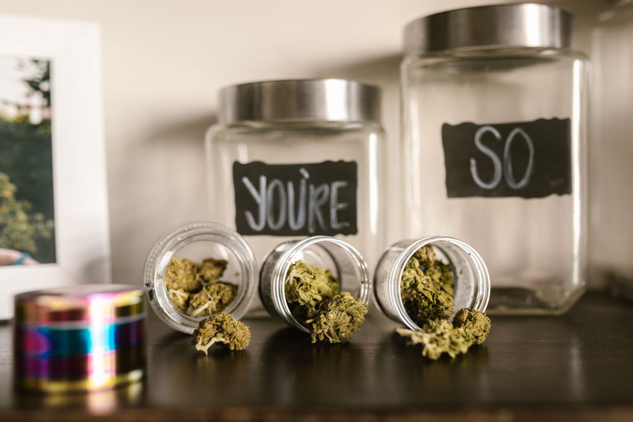 Glass jars of cannabis buds on a wooden shelf