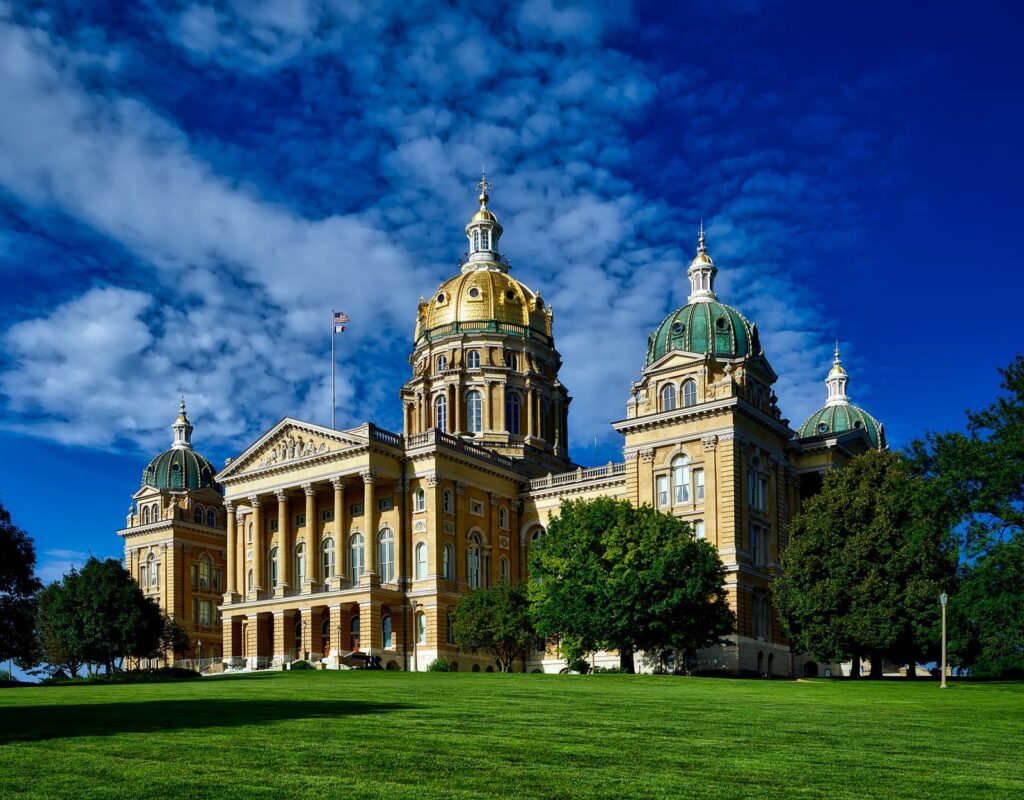 Majestic Iowa State Capitol with golden dome and lush green lawn on a clear sunny