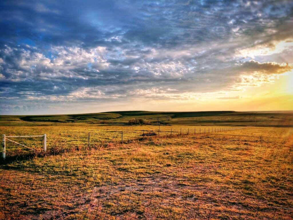 Captivating sunrise over rural Kansas landscape with grassy fields and dramatic