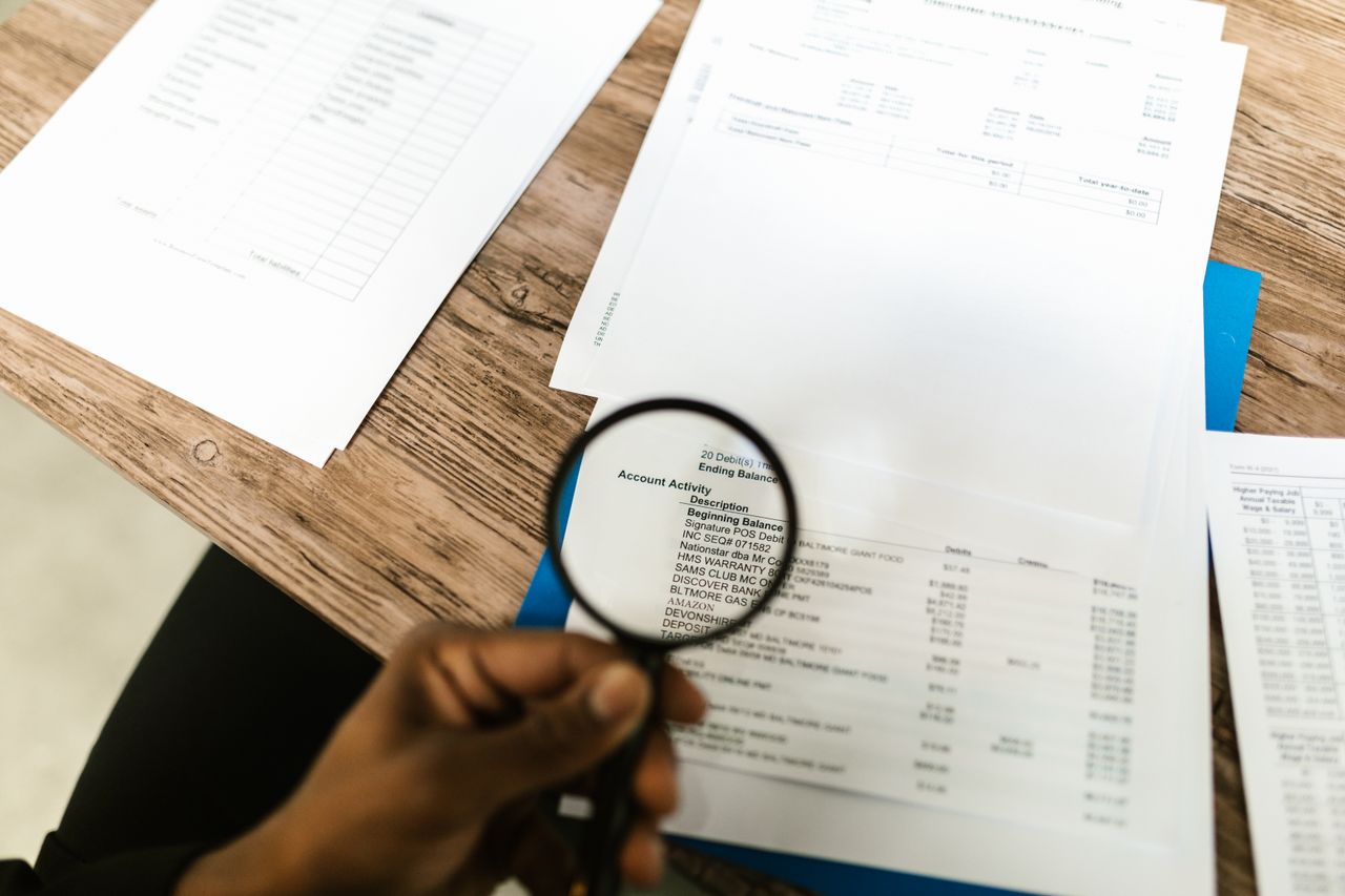 Hand using a magnifying glass to review documents