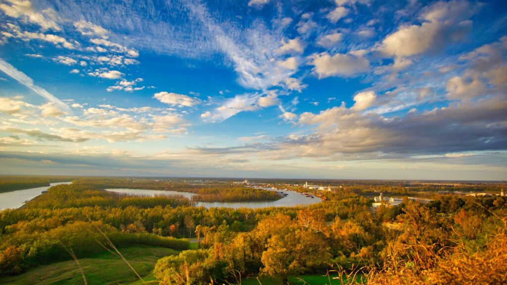 Scenic aerial view of the Mississippi River at sunset, showcasing lush greenery