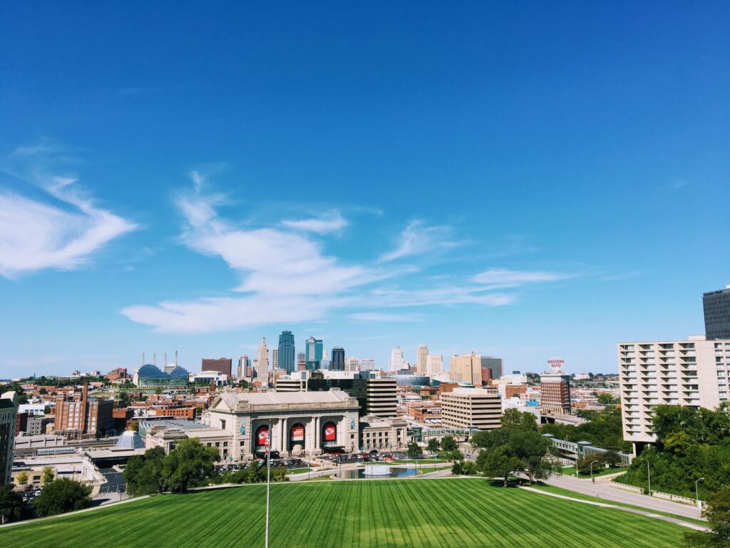 Wide-angle shot of Kansas City's skyline with clear blue skies and vibrant green