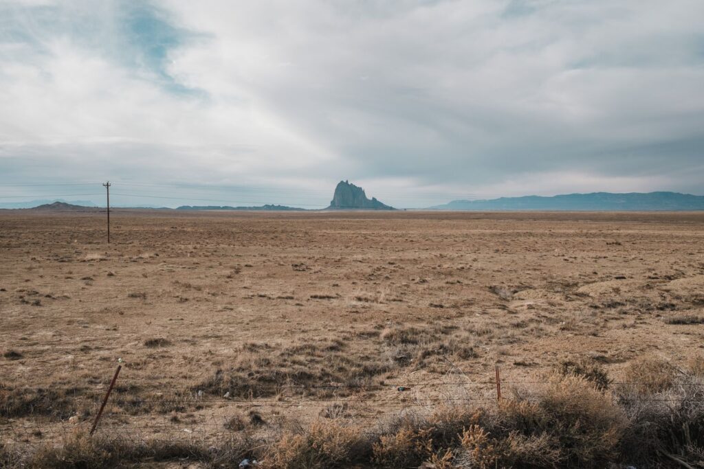 Expansive desert view of Shiprock in New Mexico, USA, under a cloudy sky