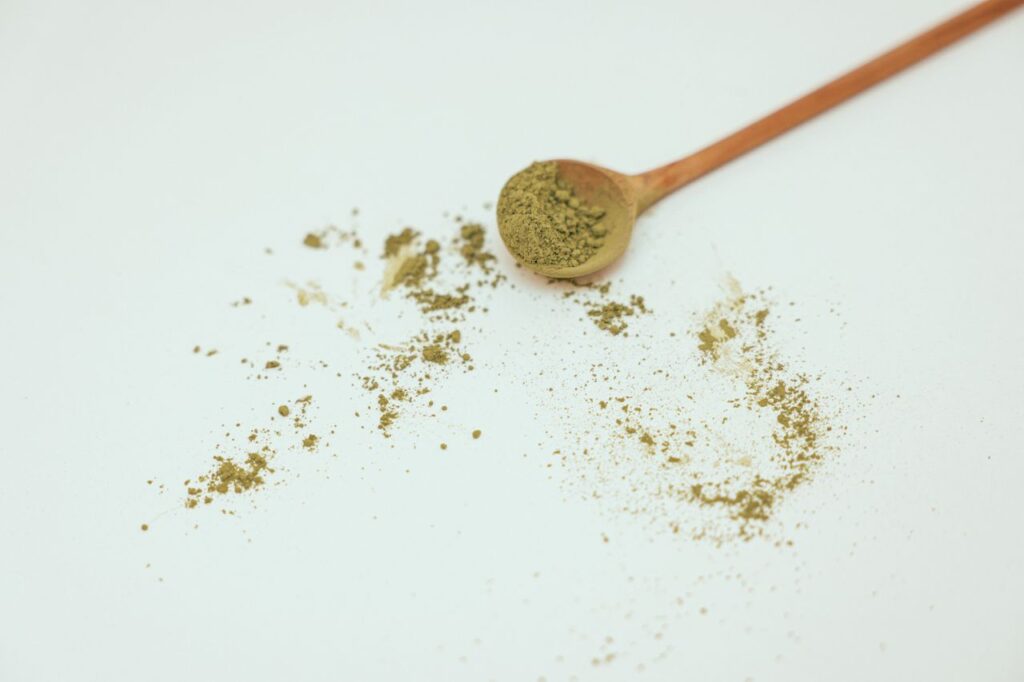 Green powder with a wooden spoon on a white surface