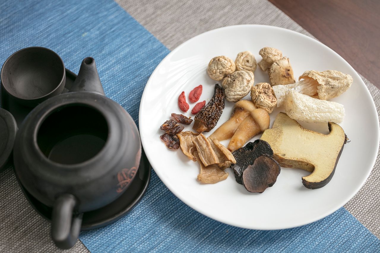 Dried Chinese herbs and mushrooms with a traditional tea set