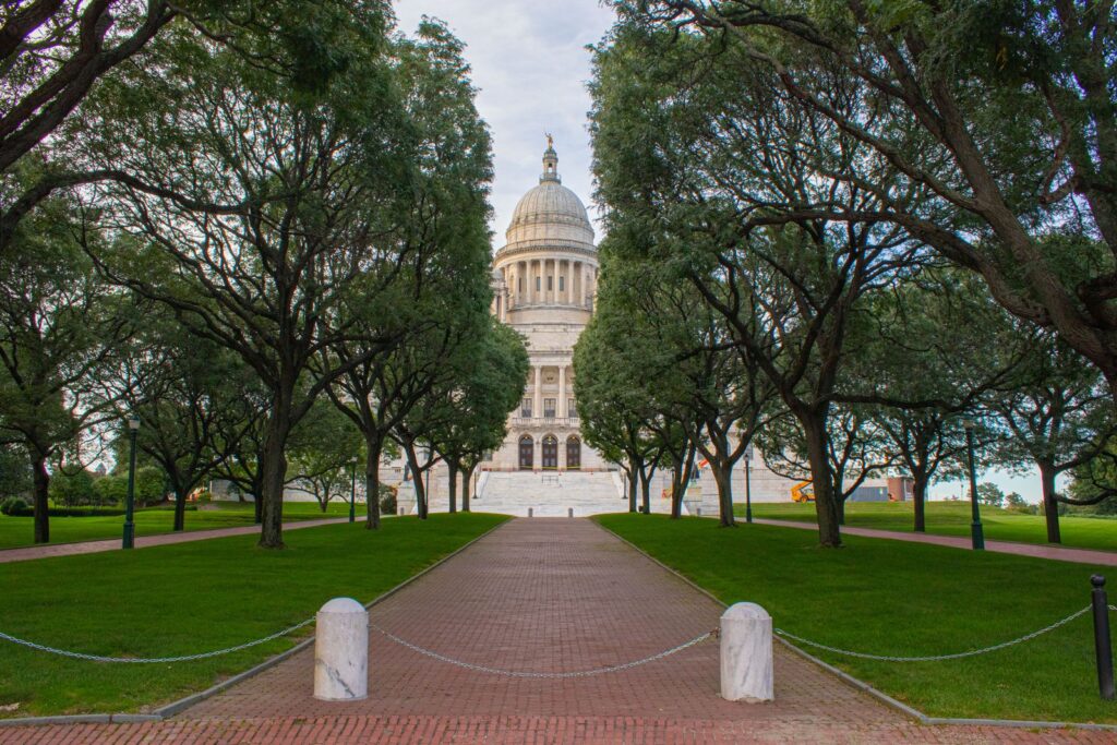The majestic Rhode Island State House surrounded by lush green trees on a sunny