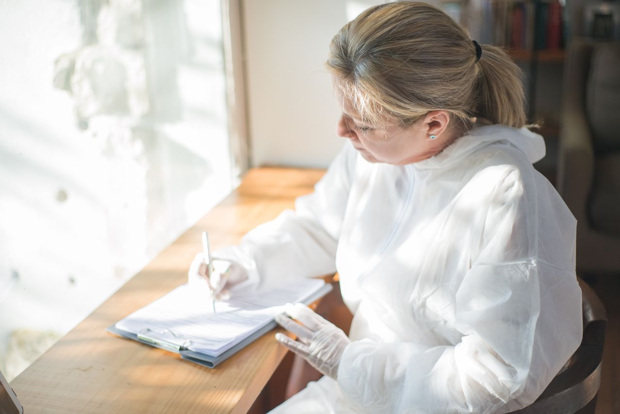 Researcher in protective gear writing in a notebook