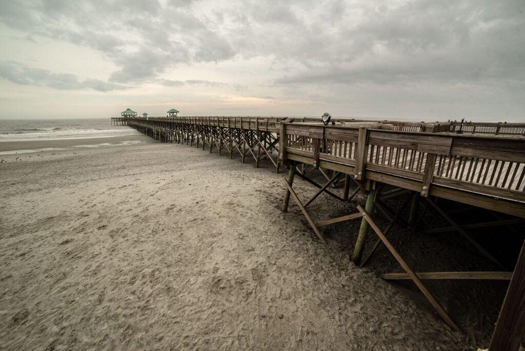 Scenic view of the wooden pier at Folly Beach, South Carolina, under a cloudy sky