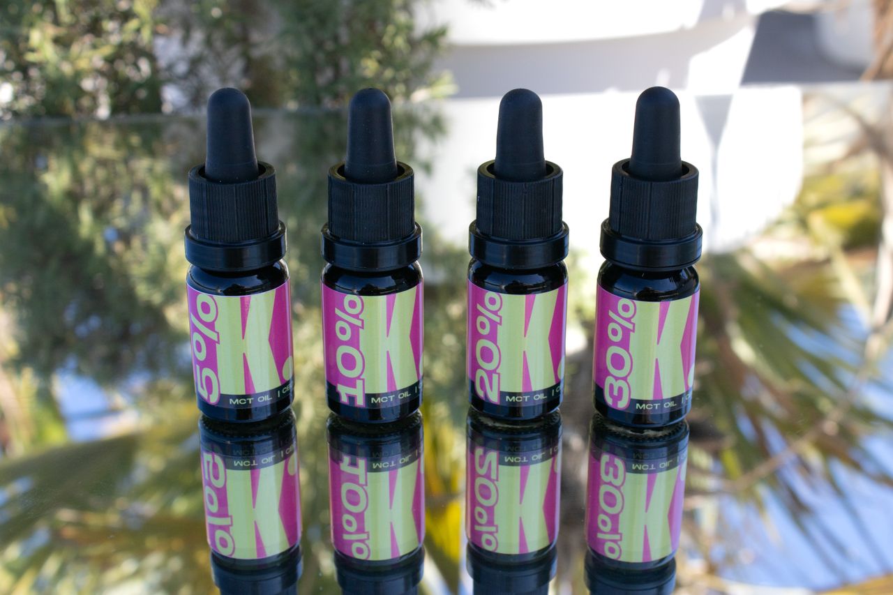 Four CBD oil bottles reflected on a surface