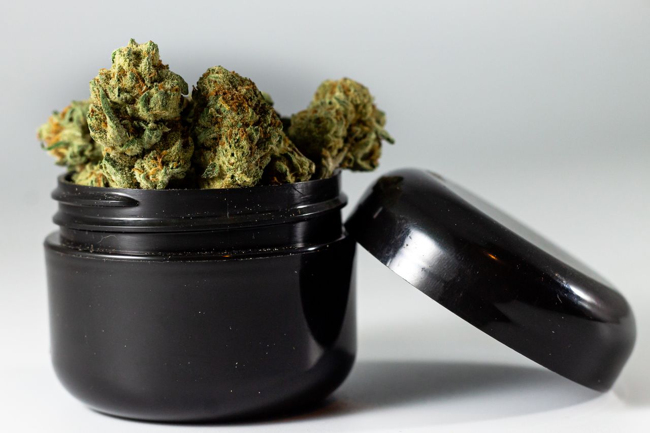 Cannabis buds overflowing from a black jar